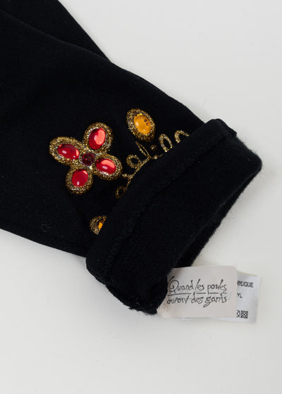 Cuff turned back to show the Quand les poules auront des gants brand label beside the red quatrefoil motif