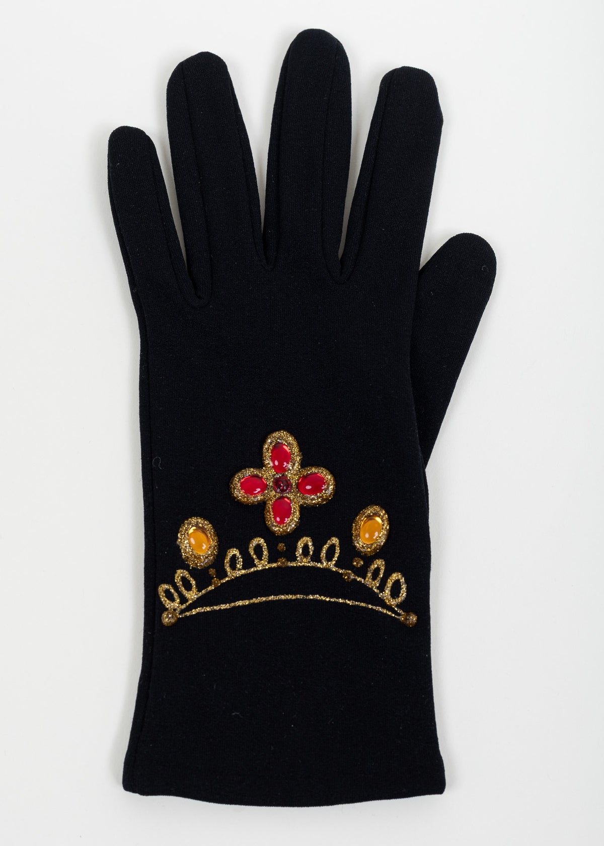 Back of one black glove with a red cabochon quatrefoil, two amber cabochons and a scalloped gold glitter necklace motif