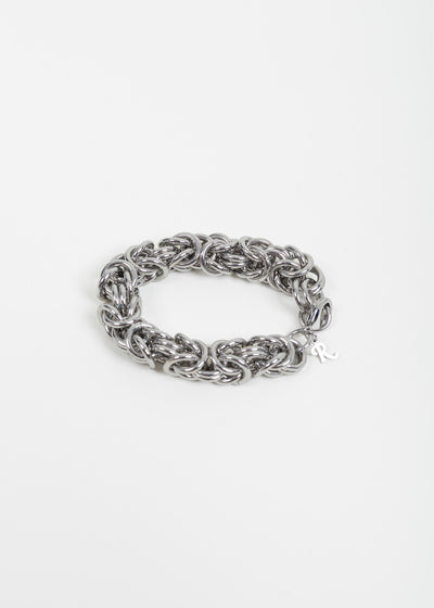 Raf Simons cluster chain bracelet laid flat on white, showing the interlocking silver-tone rings and the R charm at the clasp