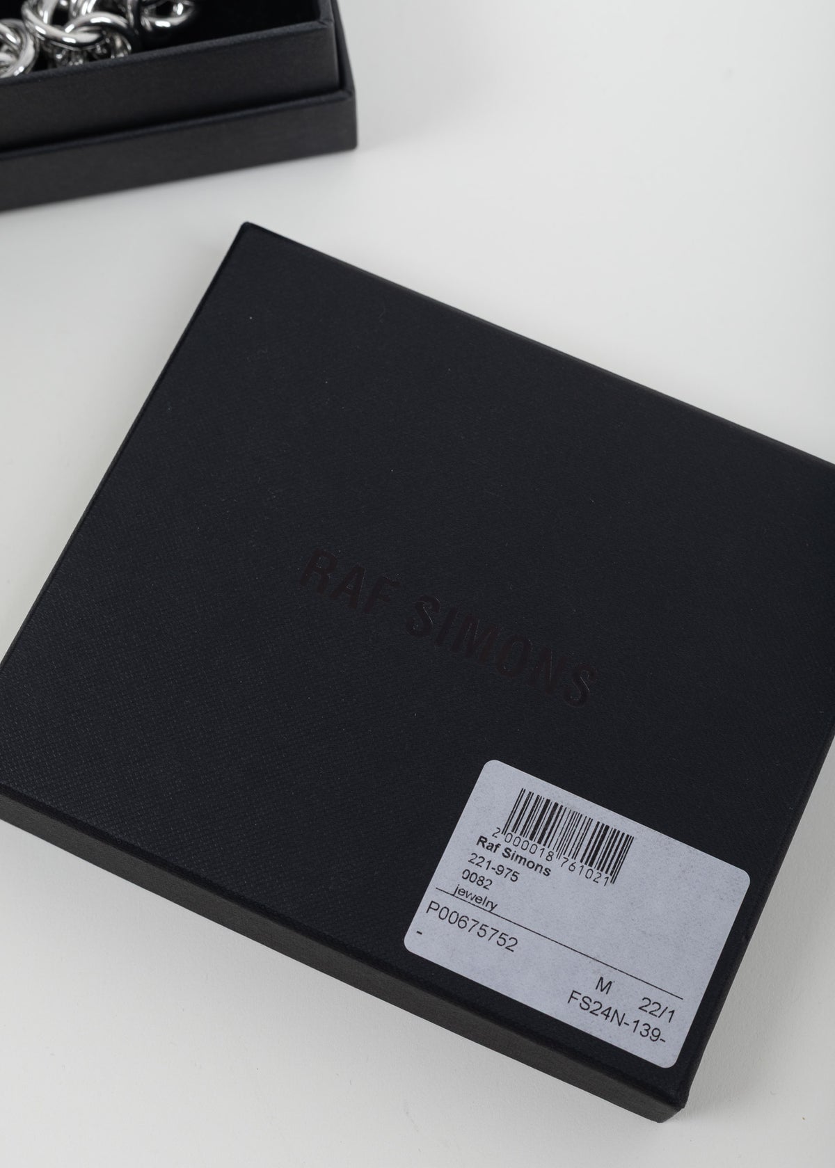 Close-up of the black Raf Simons box lid with debossed logo and product label
