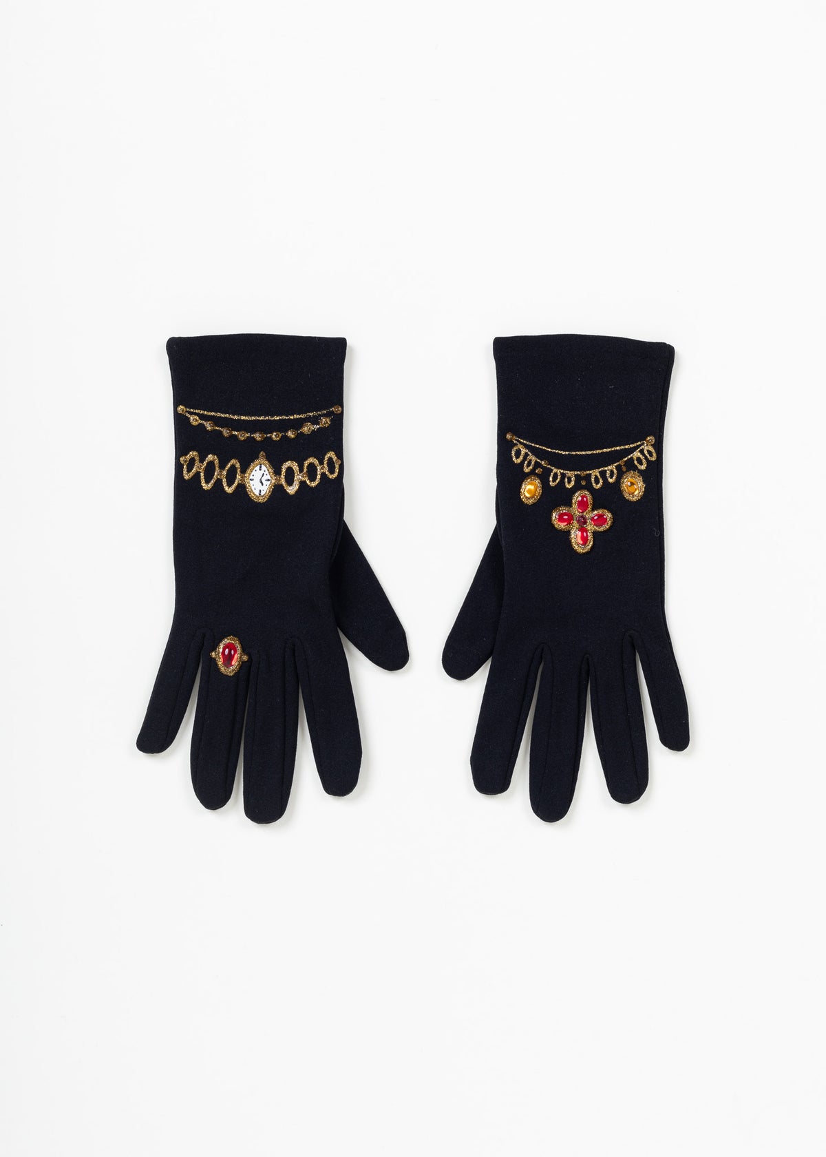 Black evening gloves side by side from above: gold glitter watch bracelet and red ring on one, necklace motif with red quatrefoil on the other