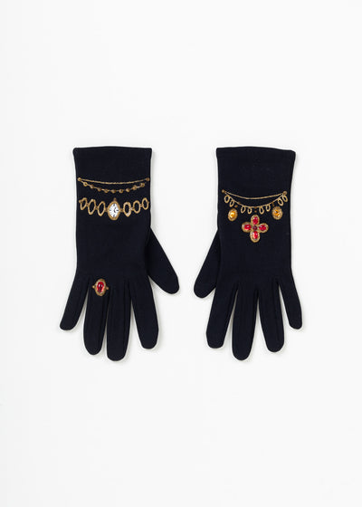 Black evening gloves side by side from above: gold glitter watch bracelet and red ring on one, necklace motif with red quatrefoil on the other