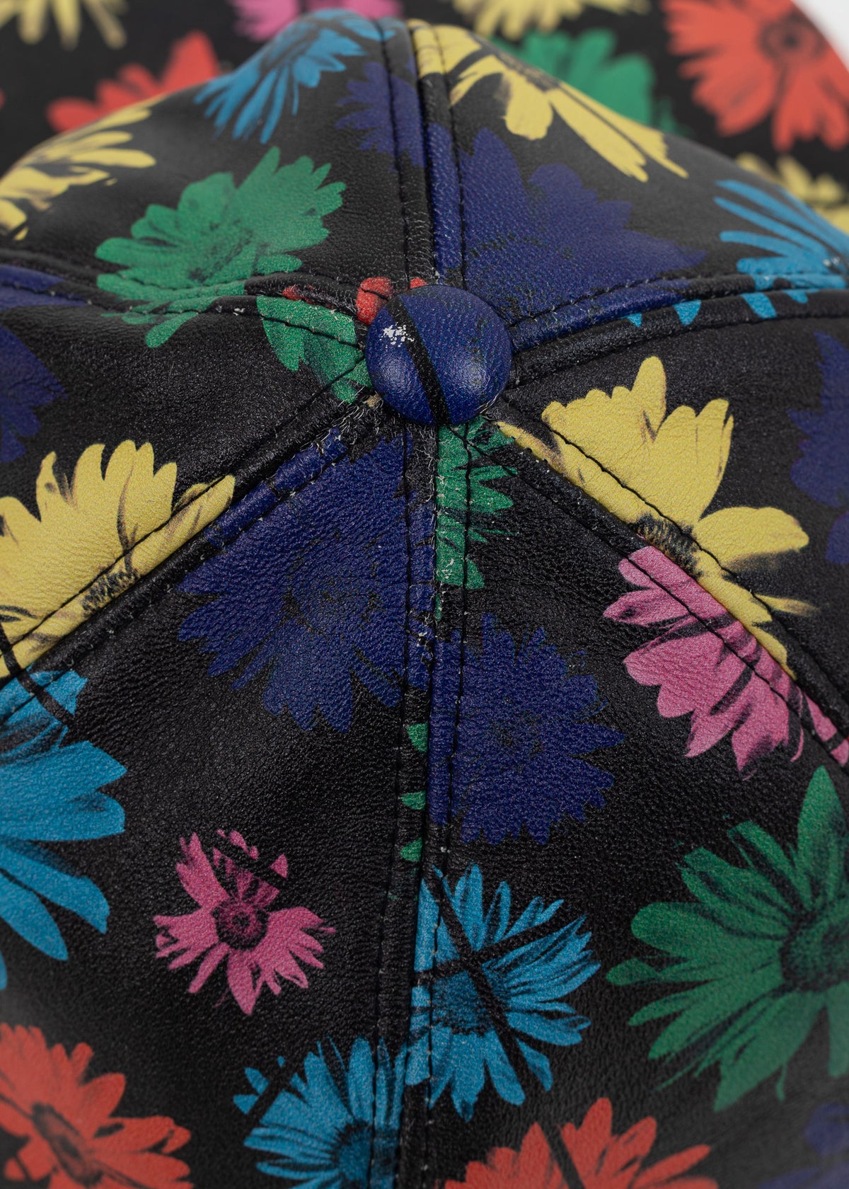 Close-up of the crown where the six printed leather panels meet at the navy covered button, with light crazing to the print